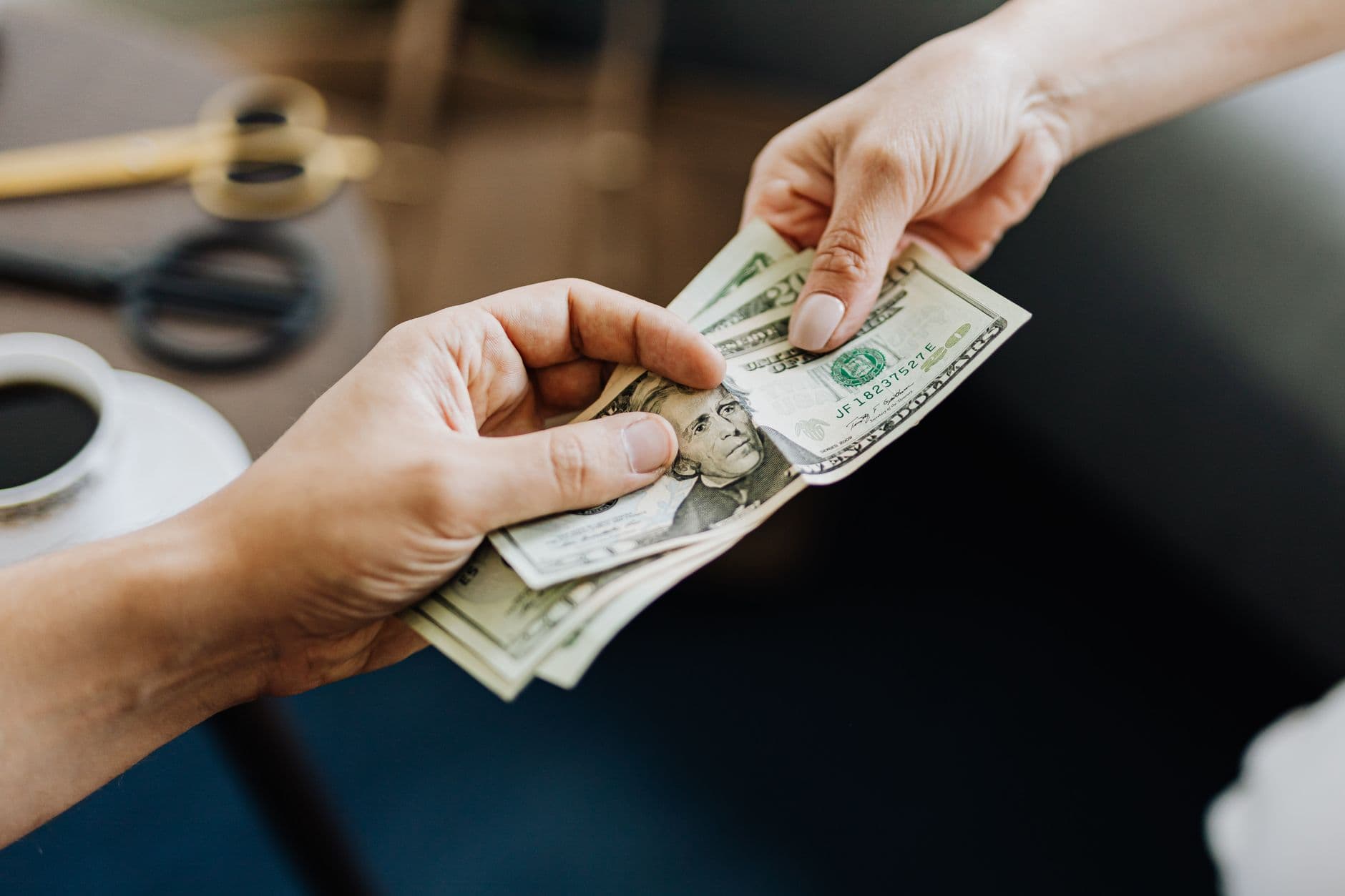One person handing banknotes to another across a table
