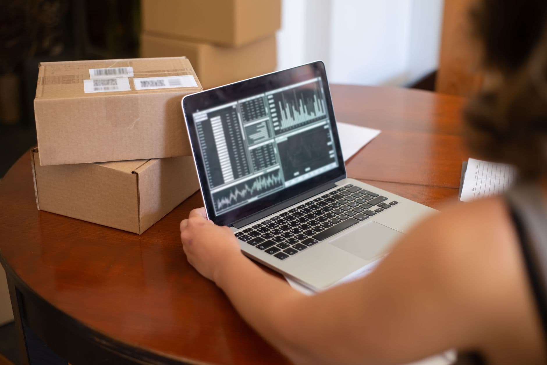 Someone checking an order on a laptop next to two stacked cardboard parcels